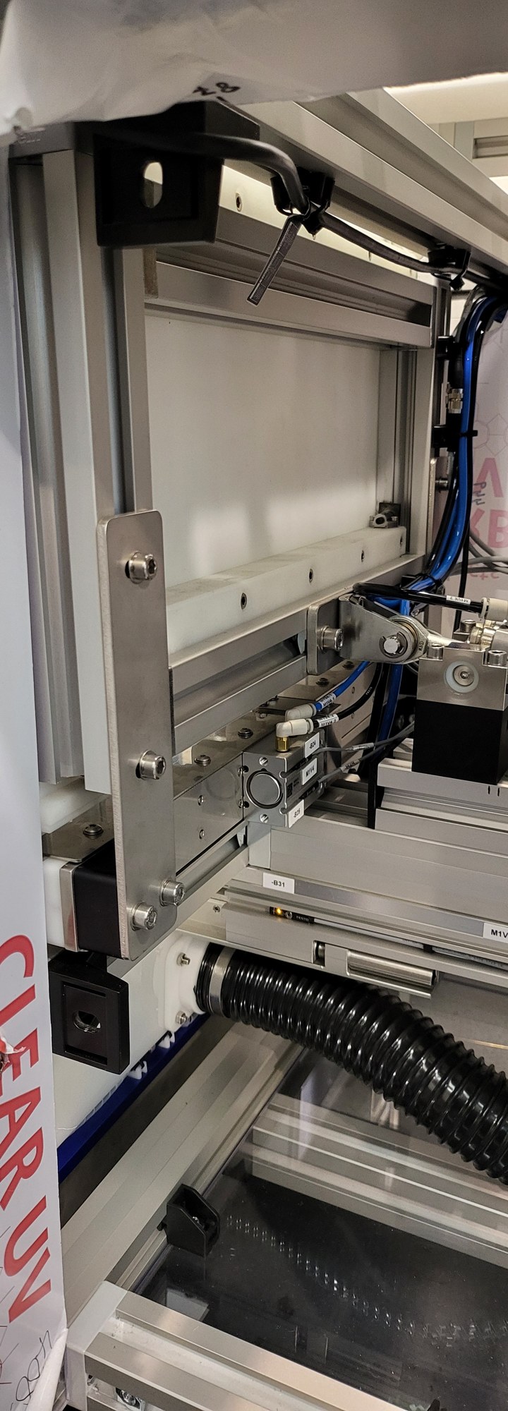 Close-up of a pneumatic cylinder, linkage and guides within an aluminium frame